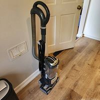 Full view of Shark Navigator Lift-Away Professional upright vacuum standing against wall