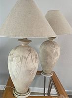 Two matching large ceramic table lamps with carved bases and fabric shades