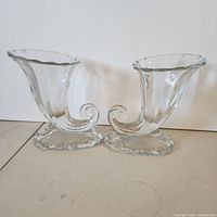 Both matching clear glass cornucopia vases front view