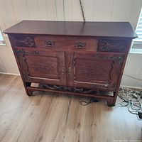 front view of carved wood sideboard showing drawers, doors, hardware