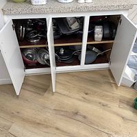 Cabinet open showing full assortment of cookware stacked on two shelves