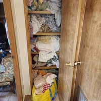 Full view of linen closet shelves and yellow bag of textiles