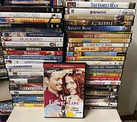 Full view of two tall stacks of DVD cases with one case displayed in front