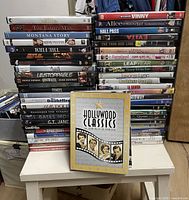 Three tall stacks of DVD cases on small table, Hollywood Classics set shown front