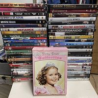 Three stacks of DVDs plus one Shirley Temple boxed set