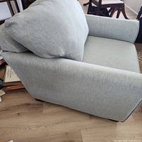 Side view of gray armchair showing upholstery, arm, cushion