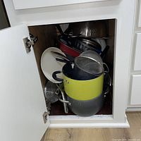 Cabinet with stockpot, mesh strainers, grill pan, platter
