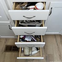 Four kitchen drawers open showing variety of utensils and flatware