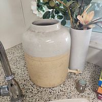 Front view of two-tone crock beside vase with faux flowers