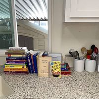 Overall view of cookbooks lined up on countertop with recipe box behind