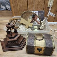 Overview of lot showing frames, cross, doily, jewelry box, pedestal stand inside plastic bin