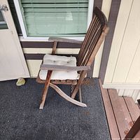 Front angled view of wooden rocking chair showing slat back, arms, rocker rails, white cushion