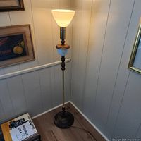 Full view of illuminated torchiere floor lamp in corner