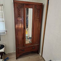Front view of solid wood armoire showing mirror door and bottom drawer