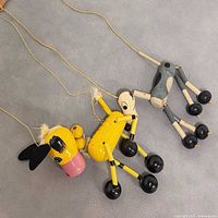 Both wooden marionettes lying flat showing bodies, limbs, strings and control bars