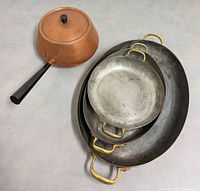 Nested set of three copper oval pans with brass handles and separate copper saucepan with lid