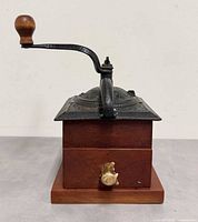 Side view showing wood base, cast iron top, crank and brass drawer pull