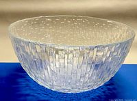 Side view of clear textured glass bowl on blue surface