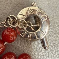 close-up of sterling silver toggle ring engraved TIFFANY & CO attached to red agate beads
