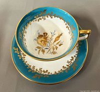 Top view showing cup interior floral spray, turquoise band and gold garland with saucer beneath