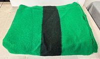 Folded green blanket with black stripe