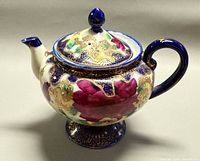 Right side view of footed porcelain teapot showing floral and gold moriage design