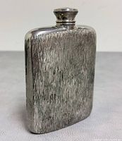 Front view of textured pewter hip flask with screw cap