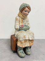 Front angle of porcelain girl figurine on suitcase