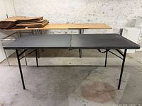 Full view of unfolded black folding table, legs extended