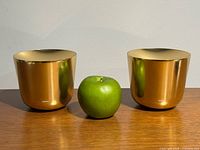 Pair of Stelton gold-tone candle holders with apple for scale