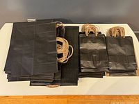 Stacks of black paper bags in three size groups