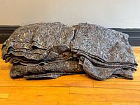 Stack of eight grey felt moving blankets folded