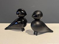 Both black lovebird figurines standing side by side