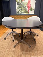 Table front angle showing top, base, chairs for scale