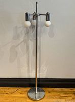 Full view of chrome floor lamp showing base, pole and three globes