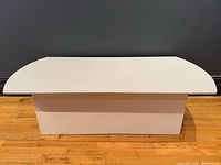 Front view of white laminate coffee table showing pedestal base and overall shape