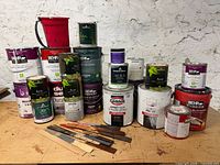 Overview of all paint cans, pail and knives on bench