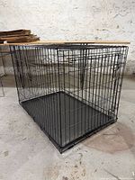 Three-quarter view of entire black wire dog crate showing overall condition and structure