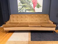 Front view showing full sofa, upholstery, button tufting, three cushions, teak legs