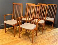 Six teak Erik dining chairs grouped, showing two armchairs and four side chairs