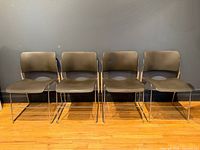 Front view of four black stacking chairs lined up