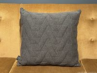 Front view of grey geometric stitched pillow on sofa