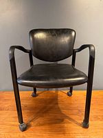 Front view of black faux leather office armchair on casters