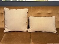 Square and rectangular beige throw pillows on sofa