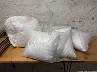 Five pillow inserts sealed in plastic on table