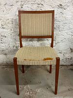 Front view of teak dining chair showing torn seat upholstery and overall wear