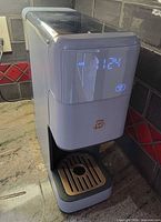 Front view of coffee maker powered on showing LED display and drip tray