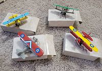 Four painted die-cast biplanes on individual sleeves