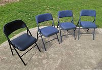 Group view of four folding chairs showing three blue fabric chairs and one black vinyl chair
