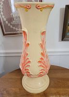 Front view of cream ceramic vase with orange foliate relief